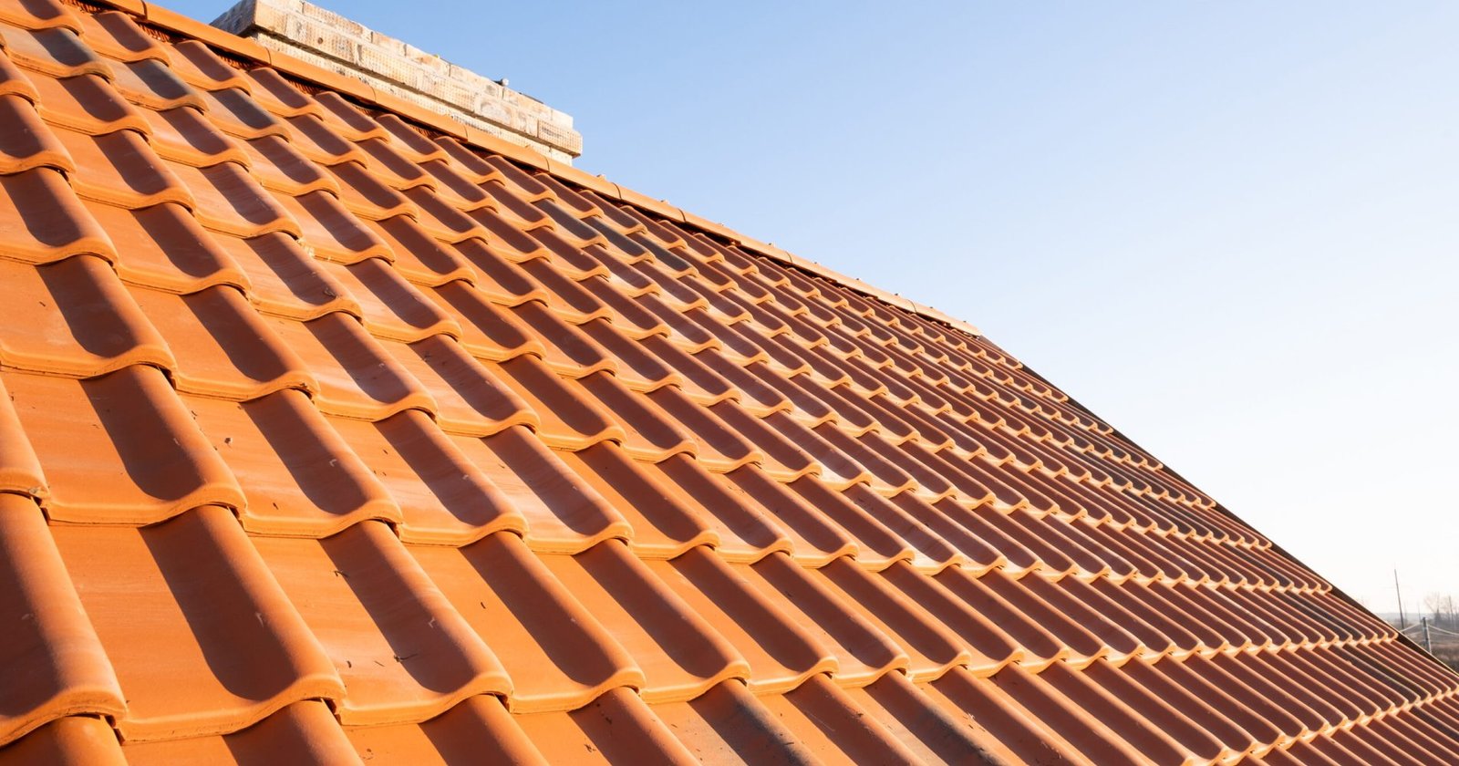 Overlapping rows of yellow ceramic roofing tiles covering residential building roof.
